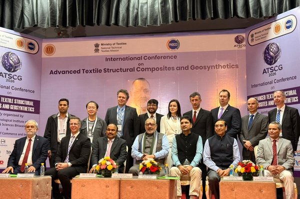 Mehrere Personen sitzen und stehen auf einer Bühne für ein Gruppenfoto